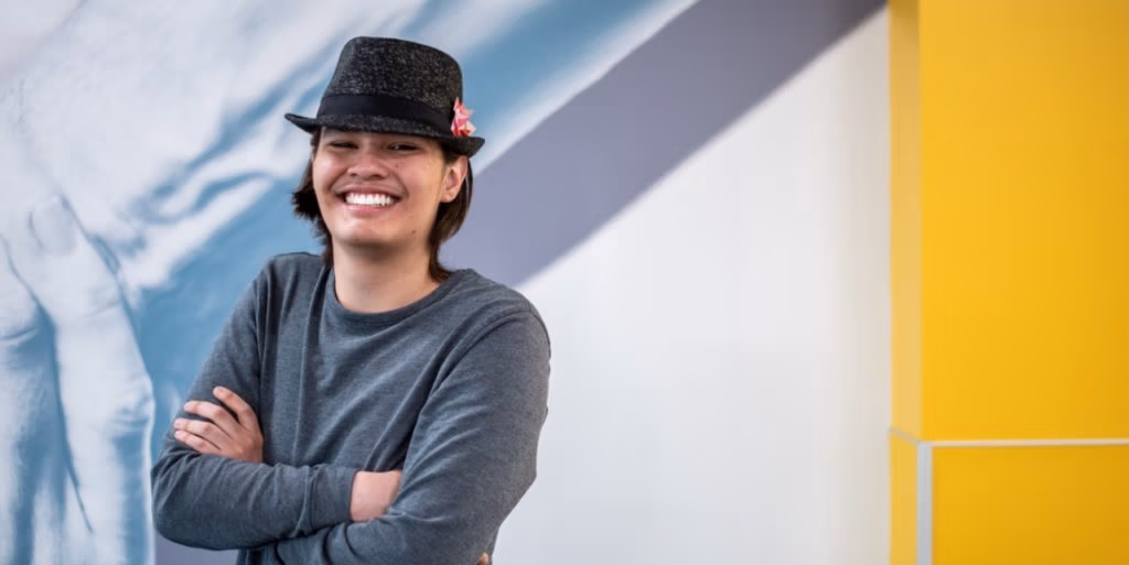 Jesus standing with his arms crossed in front of a colorful wall inside CEC Douglas County North.