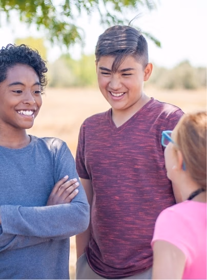 Three students standing around outside talking.