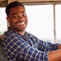 Close-up image of a man in a plaid shirt driving a bus.