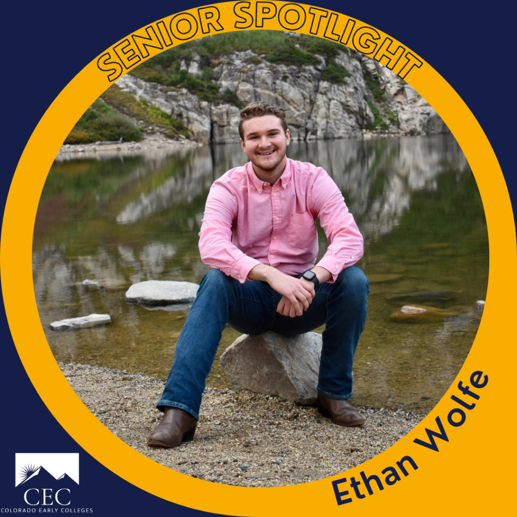 Aluno em destaque: Ethan Wolfe. Ethan está sentado em uma pedra em frente a um lago na montanha.