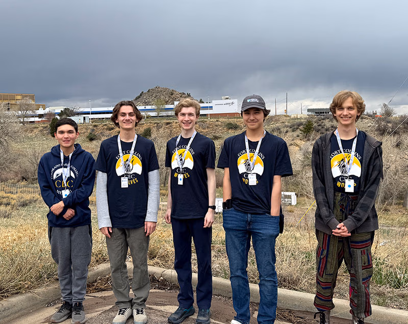 Students from the CECFCHS Coding Club team. Five students standing with a field and buildings behind them.