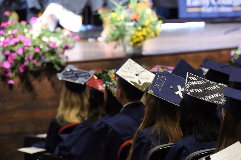 CEC Fort Collins High School graduation students photographed from the back. The students are wearing blue caps and gowns.