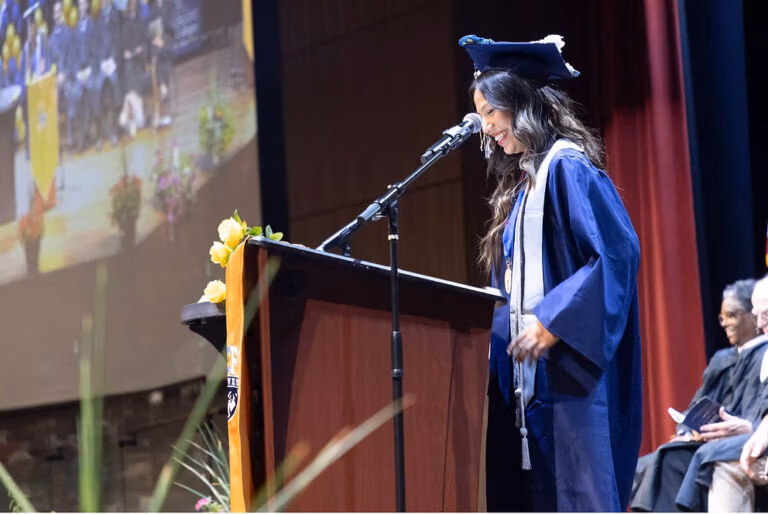 CEC Fort Collins graduate Mera Sanchez giving a graduation speech at a podium.