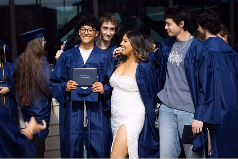 CEC Fort Collins High School graduates in dark blue caps and gowns standing outside after they graduated.