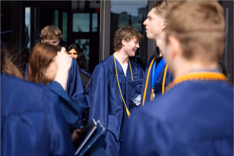CEC Fort Collins High School graduates in dark blue caps and gowns standing outside after they graduated.