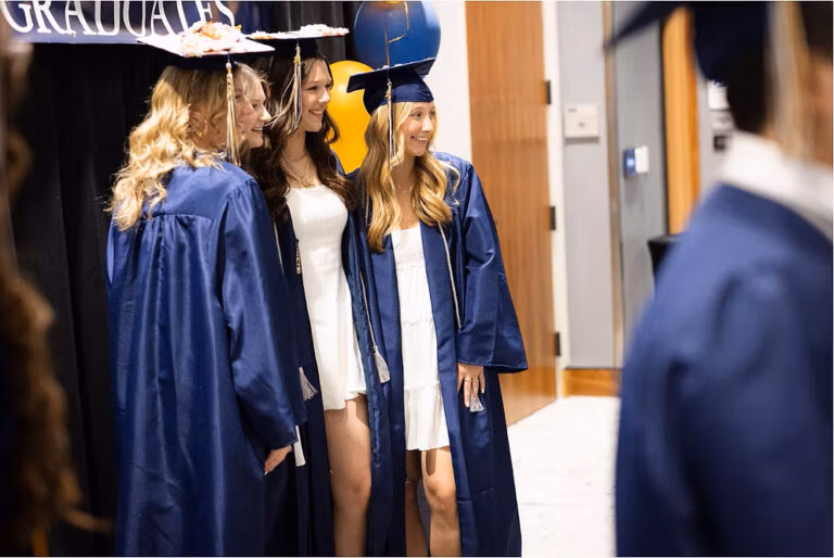 CEC Fort Collins High School graduates in dark blue caps and gowns posing for a picture.