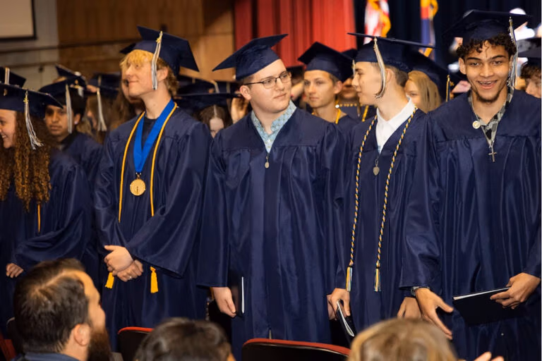 CECFC 2025 Graduates standing in their cap and gowns holding their diplomas.