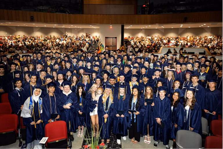 2025 CEC Fort Collins High School graduates standing in a group after they graduated in dark blue caps and gowns.
