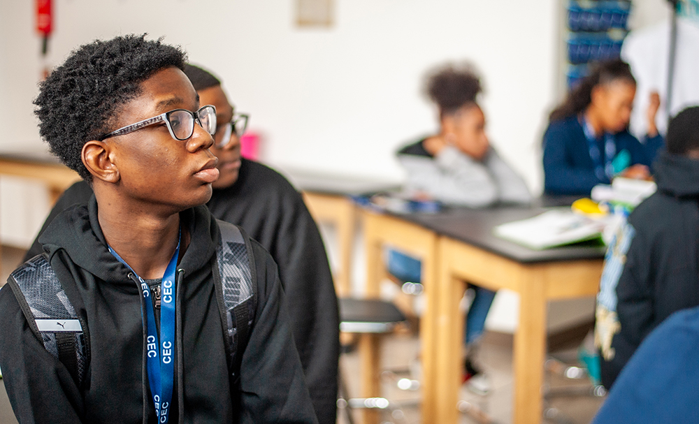 CECA student sitting in class with his backpack on looking off into the distance.