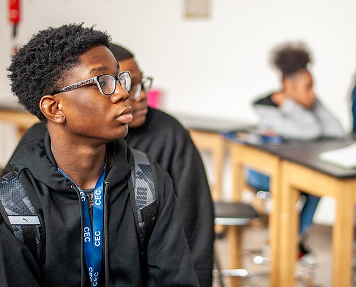CECA student sitting in class with his backpack on looking off into the distance.