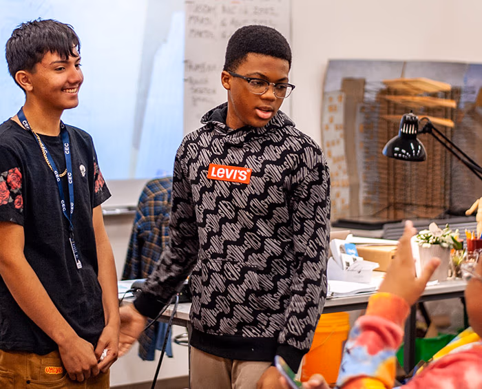 Two students talk with another CECA student after they finish a presentation at the front of the class.