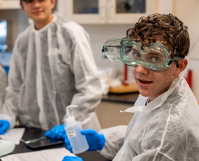 CECCR student looking at the camera wearing protective goggles, gloves and a smock.