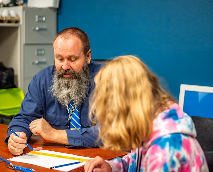 CECCS student sitting at a desk working with the teacher.