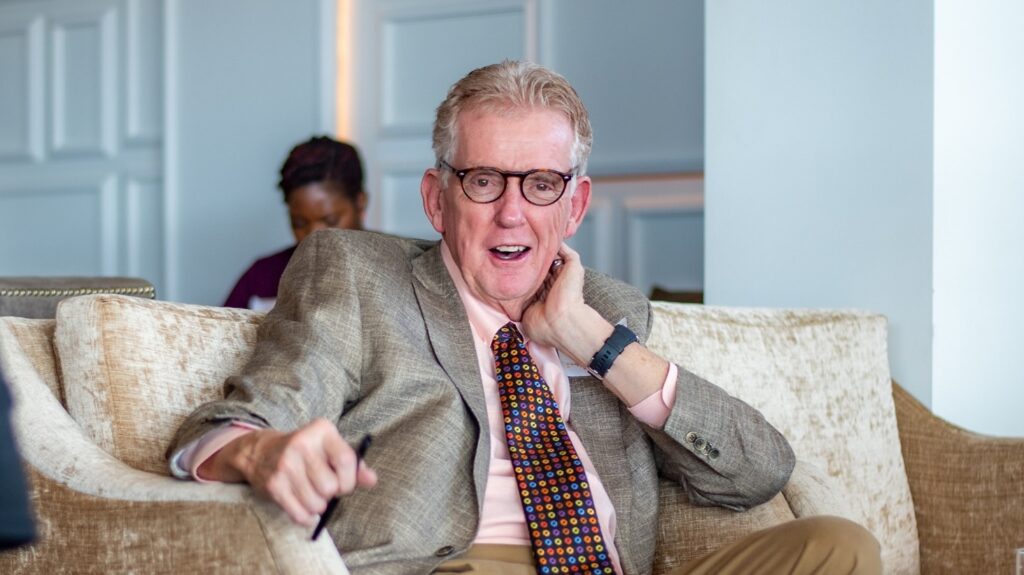Founder Keith King sitting in a chair wearing a suit.