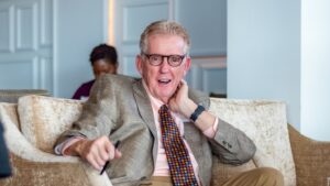 Founder Keith King sitting in a chair wearing a suit.