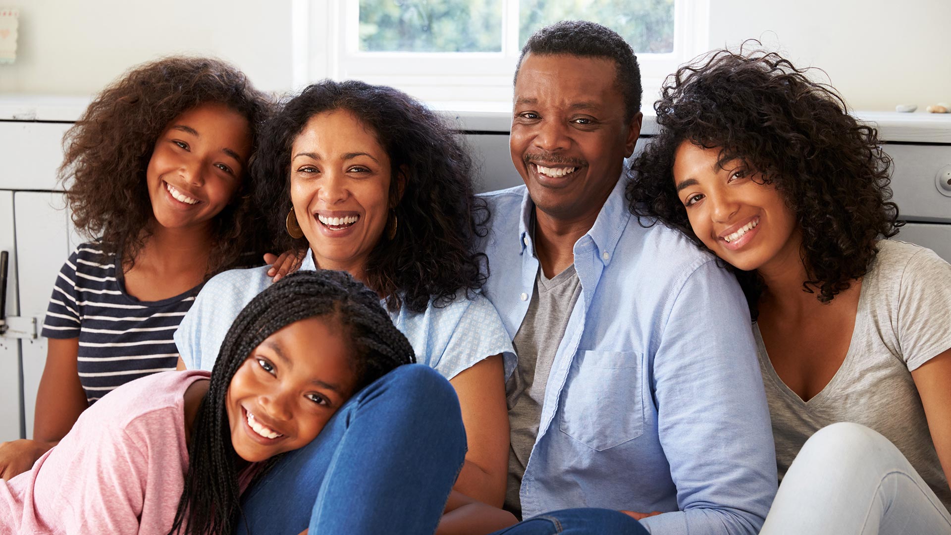 Family of 5 sitting in a group looking at the camera.