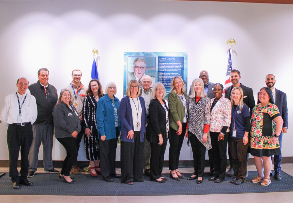 Faculty and board members pose for a photo in front of a Keith King plaque that was recently installed to celebrate Keith King Day and CEC Colorado Springs.