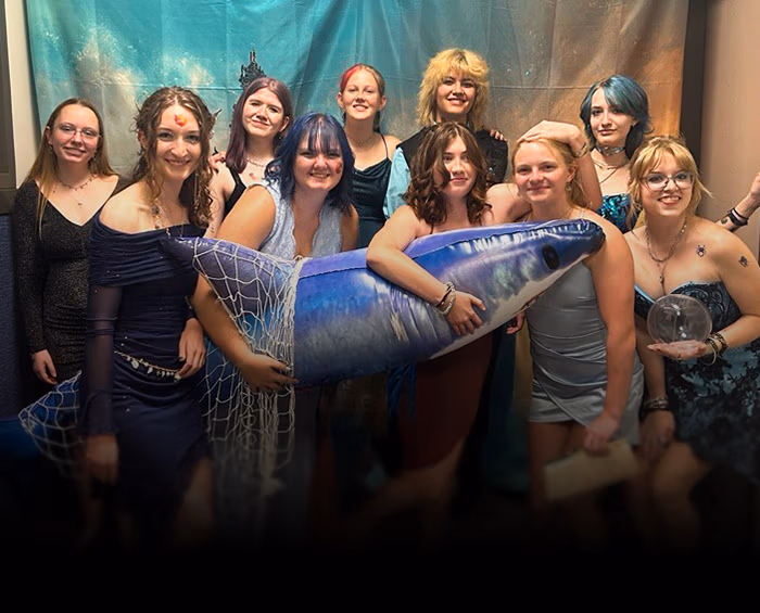 CEC Castle Rock high school students pose with ocean themed props in front of a backdrop for a photo during the school dance.