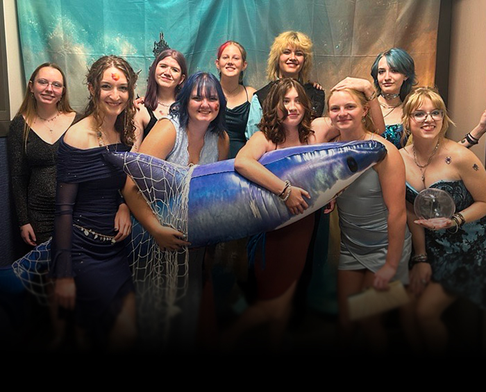 CEC Castle Rock high school students pose with ocean themed props in front of a backdrop for a photo during the school dance.