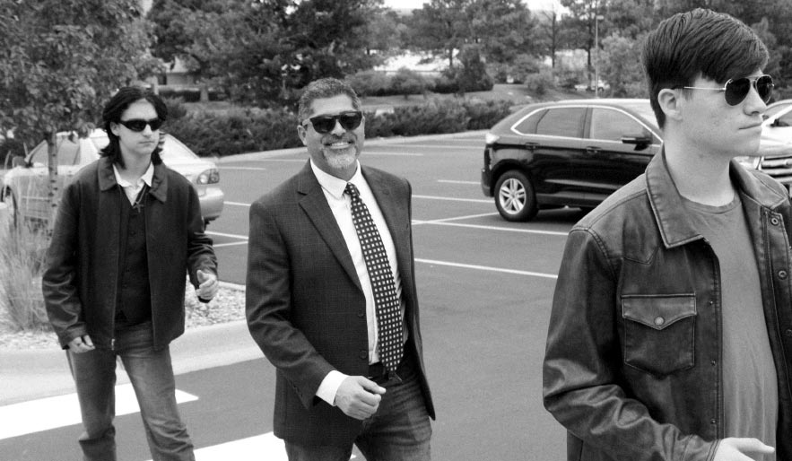 Head of School Toso Chavez walks with two students across a crosswalk.