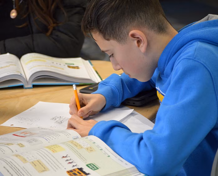 CECFC Middle School student works on schoolwork in a classroom.