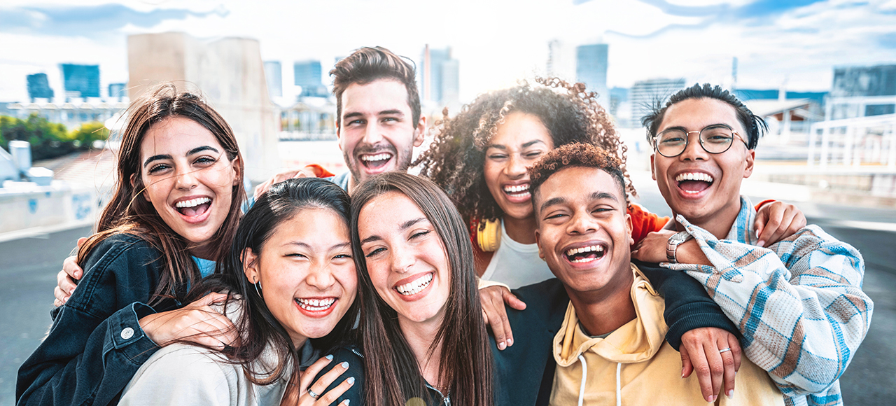 Happy group of young people smiling at camera outdoors.
