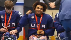 Paralympic Champion Malik Jones in a hockey uniform with a gold medal next to his teammates.