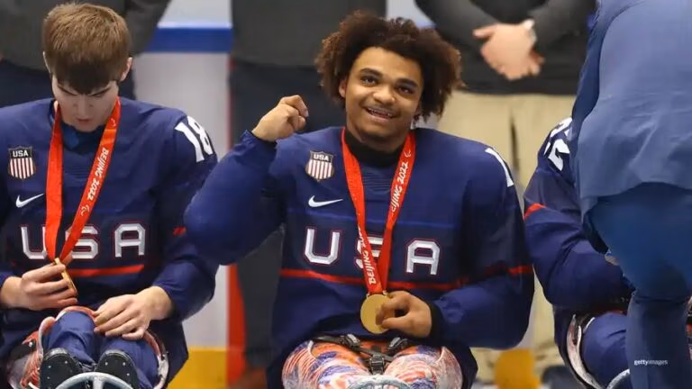 Paralympic Champion Malik Jones in a hockey uniform with a gold medal next to his teammates.