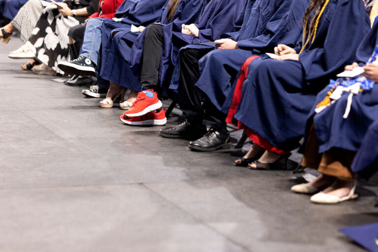 Candid image of CEC Fort Collins High School graduates shoes in the front row at graduation.