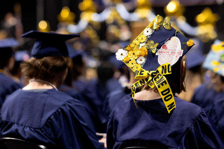 CEC Fort Collins Highs School graduate cap that says "forensic science" and has flowers and butterflies glued to it.