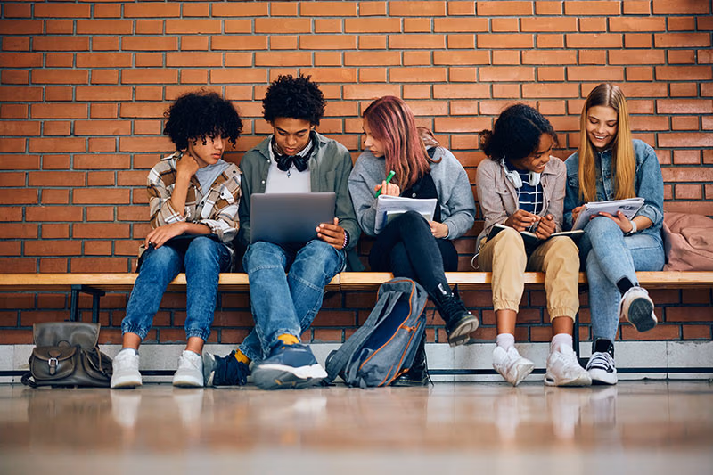 CEC Students sitting on a bench studying in a hallway at school.