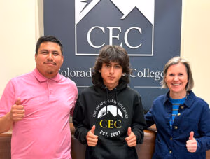 Daniel Pina Hernandez, a graduate of CEC Aurora and two others pose for a picture in front of a CEC sign.