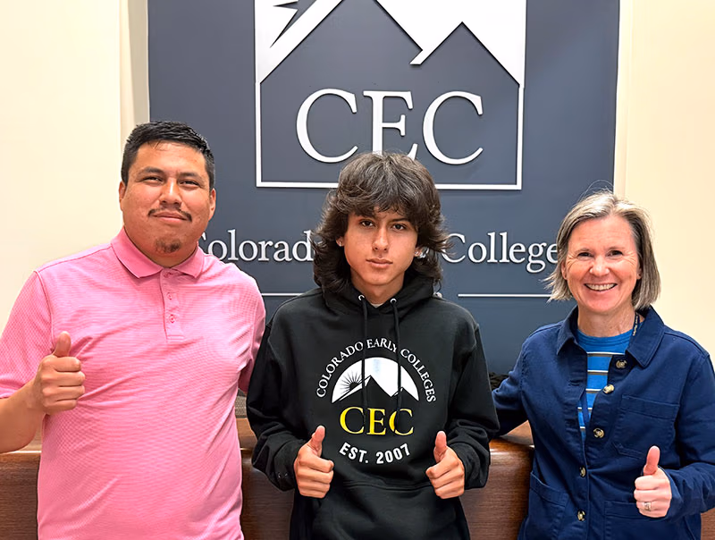 Daniel Pina Hernandez, a graduate of CEC Aurora and two others pose for a picture in front of a CEC sign.